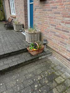 three baskets with plants in them sitting on a brick wall at Ferienhaus Leegwater in Munkmarsch