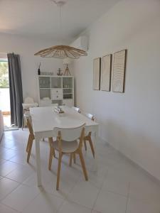 a white dining room with a white table and chairs at Albur Beach House in Alvor