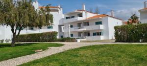 a white apartment building with a tree and a walkway at Albur Beach House in Alvor