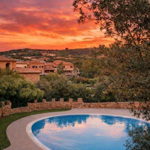 a swimming pool in a yard with a sunset in the background at Tortuga Smeralda in Porto Rotondo