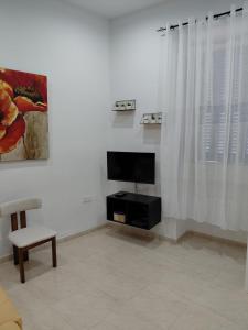 a living room with a television and a chair at Charming Ground-floor Maisonette in Birgu