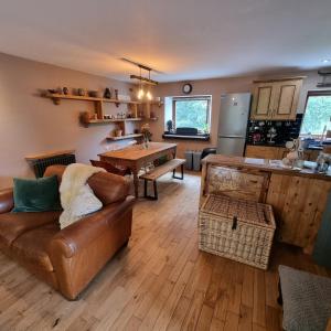 a living room with a leather couch and a kitchen at Calderbrook House in Hebden Bridge