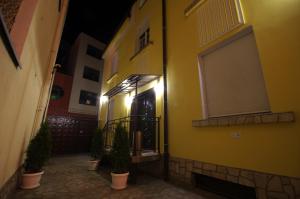 a yellow building with potted plants in front of a door at Guest House "The House" Топ Център Габрово in Gabrovo
