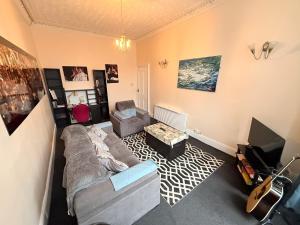 a living room with a couch and a television at Paisley Pad Glasgow Gateway second floor flat in Paisley