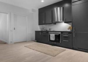 a kitchen with black cabinets and a stove at Prime Central Oslo - Frogner, All-Inclusive Apartment in Oslo