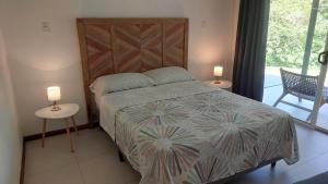 a bedroom with a bed with two tables and two lamps at Villas Pura Vida - Marañón in Puntarenas +18 photos