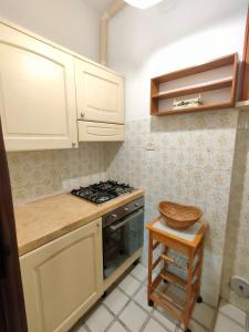 a kitchen with white cabinets and a stove and a stool at I Tre Archi in Suvereto