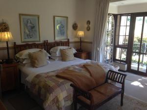 a bedroom with a bed and a chair and windows at Periwinkle Blue in Clarens