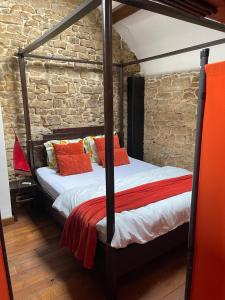 a bedroom with a four poster bed with orange pillows at Grange de la Rochette - 1 à 6p in Jamoigne