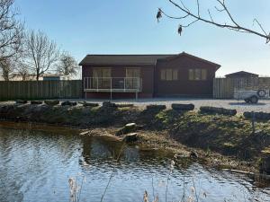 a house next to a body of water at Star Carr Lakes in Great Driffield