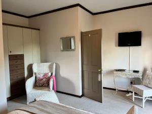 a bedroom with two chairs and a tv on the wall at Periwinkle Blue in Clarens