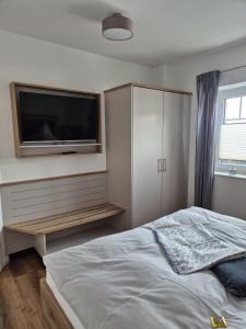 a bedroom with a bed and a flat screen tv at Kleine Hafenperle Büsum in Büsum