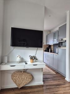 a white kitchen with a tv on the wall at Kleine Hafenperle Büsum in Büsum +22 photos