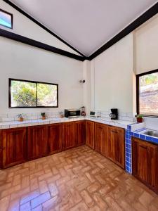 a large kitchen with wooden cabinets and windows at Casa Rural Los Almendros - Tarcoles in Capulín