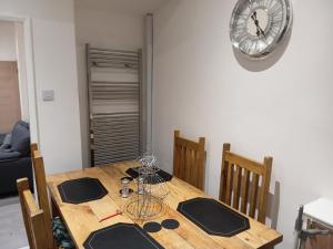 a wooden table with chairs and a clock on the wall at Dale combe in Middleton +2 photos