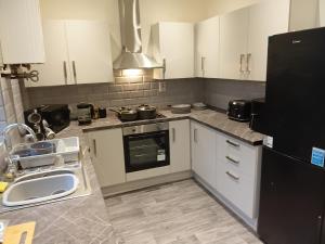 a kitchen with white cabinets and a sink and a refrigerator at Dale combe in Middleton