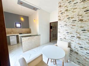 a kitchen with a white table and a brick wall at Apart hotel Refúgio tropical Icarai de amontada in Amontada