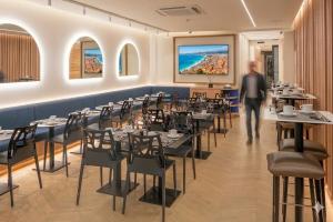 a man walking through a restaurant with tables and chairs at Hotel 64 Nice in Nice