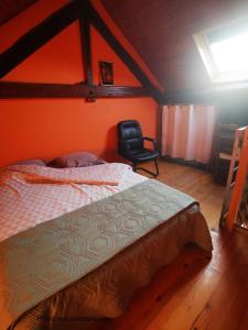 a bedroom with a bed and a black chair at Les racines Bohèmes in Avèze