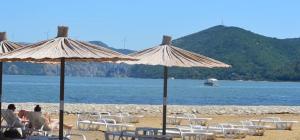 a group of people sitting under umbrellas on a beach at Apartmani Đorđević 2 in Golubac +6 photos