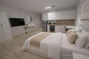 a bedroom with a large white bed and a kitchen at Modern Studio Near Al Haram And City Center Self Check-in in Medina