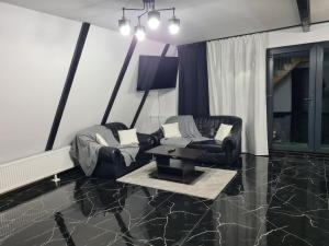 a living room with two chairs and a table at A frame Ina și Cristi in Tîrsa
