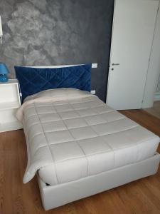 a white bed in a bedroom with a blue pillow at A 2 passi dal mare in Scardovari