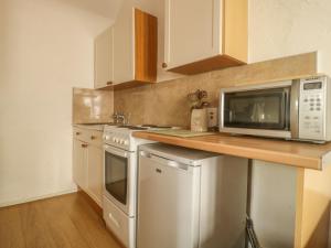 a kitchen with a microwave and a stove top oven at Mews Cottage 7 in Keswick +5 photos