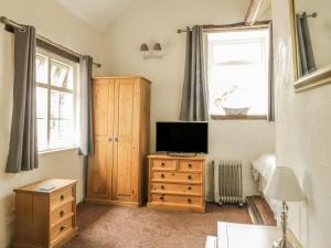 a bedroom with a television on a dresser and a window at Mews Cottage 7 in Keswick
