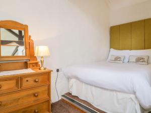 a bedroom with a bed and a mirror and a dresser at Mews Cottage 6 in Keswick
