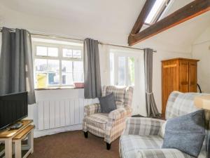 a living room with two chairs and a tv at Mews Cottage 6 in Keswick