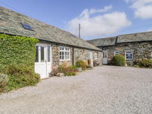 an exterior view of a stone house with a driveway at Mews Cottage 6 in Keswick