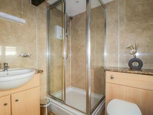 a bathroom with a shower and a toilet and a sink at Mews Cottage 6 in Keswick +4 photos