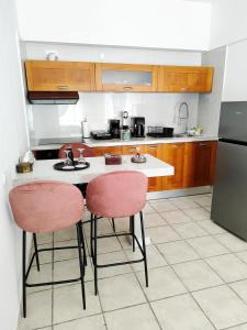a kitchen with a sink and two pink chairs at Sweet Home Suite in Korinthos