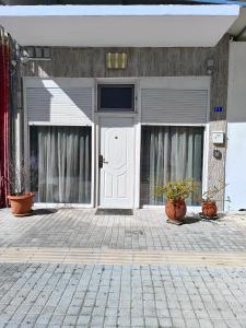 a building with a white door and two potted plants at Sweet Home Suite in Korinthos