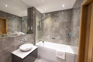 a bathroom with a tub and a sink and a shower at Royal Gardens Apartment 10 in Dornoch