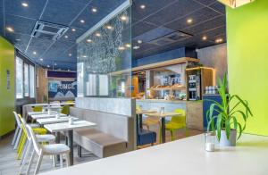 a restaurant with white tables and yellow chairs at Ibis Budget Toulon Centre in Toulon