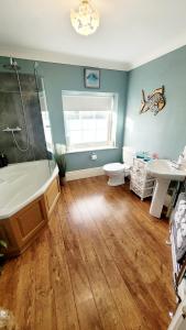 a bathroom with a tub and a toilet and a sink at Three Farthings in Cranswick