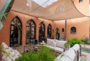 an outdoor patio with white couches and a pool at Riad Malak Palmeraie in Marrakesh