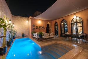 a swimming pool in a room with a table and chairs at Riad Malak Palmeraie in Marrakesh