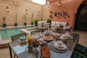 a table with food on it next to a pool at Riad Malak Palmeraie in Marrakesh