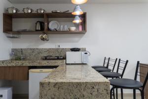 a kitchen with a counter with chairs and a microwave at Tambaú Beira-Mar in João Pessoa