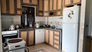 a kitchen with wooden cabinets and a white refrigerator at Bozcaada Bag Evi in Bozcaada