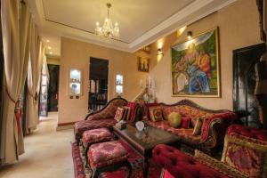 a living room with a red couch and chairs at Riad Malak Palmeraie in Marrakesh