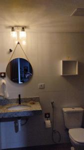 a bathroom with a sink and a mirror and a toilet at Central Apartment 03 in Ouro Preto