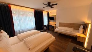 a hotel room with two beds and a ceiling fan at Hotel Antares München in Munich