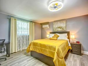 a bedroom with a yellow bed and a television at Private Guest House 10 Min to Airport & Downtown in Jacksonville