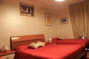 a bedroom with two beds with red sheets at Alice Affittacamere in Cesana Torinese