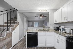 a kitchen with white cabinets and a staircase at Modern 2BR townhome with full kitchen & dining in Arlington
