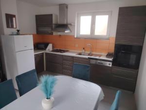 a kitchen with a white table and blue chairs at Apartman ŠIPA in Bjelovar